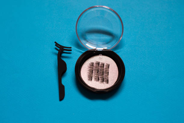 Magnetic lashes in a case with an applicator tool on a blue background.