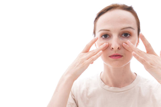 Person applying makeup under their eyes to correct dark circles.